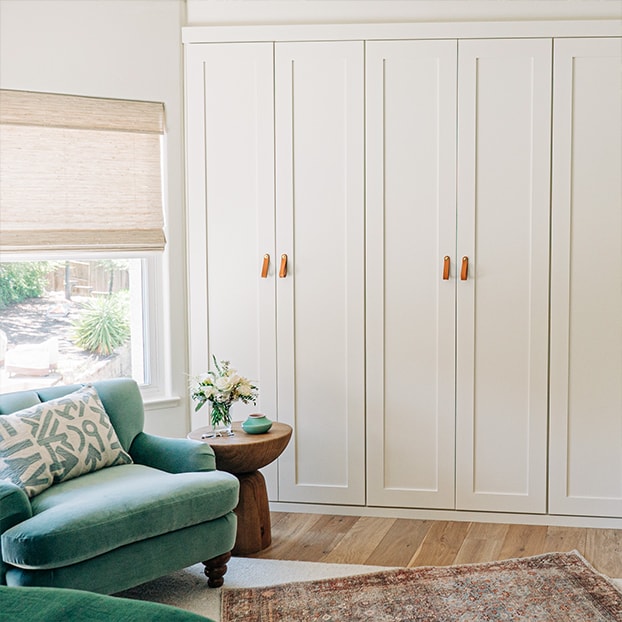 White cabinetry and a green armchair